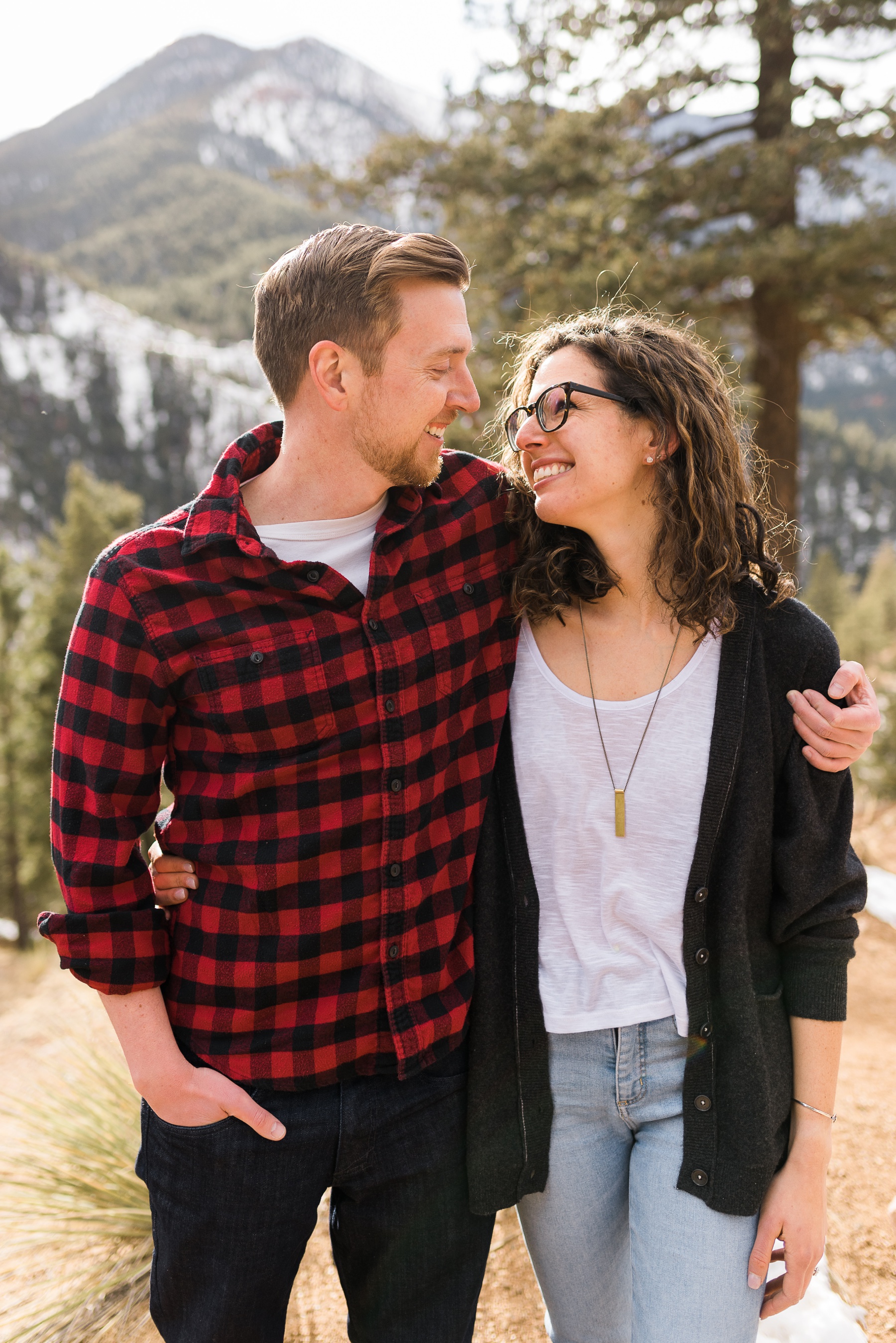 Man in red and black checked shirt and woman in navy blue sweater smiling at each other