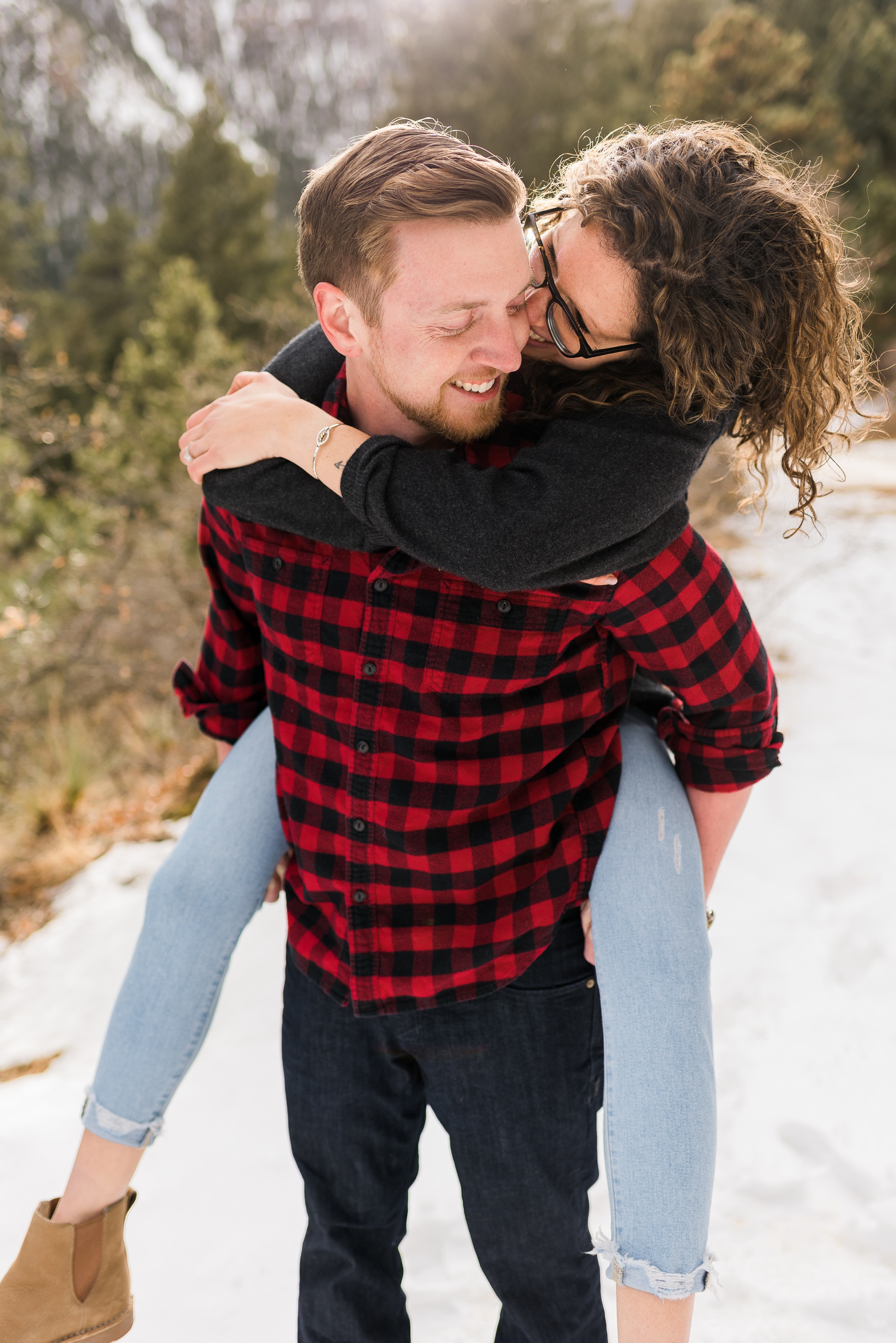 Man smiling with woman piggy back for engagement photos