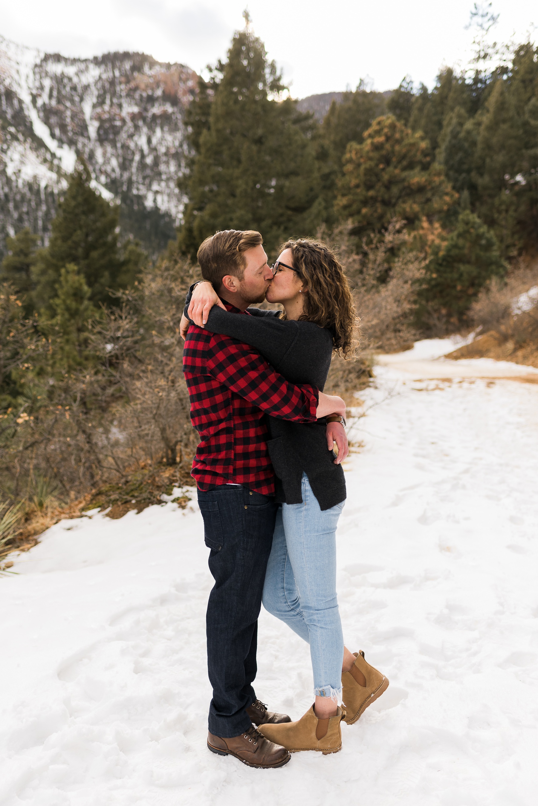 couple kissing for engagement photos with mountains
