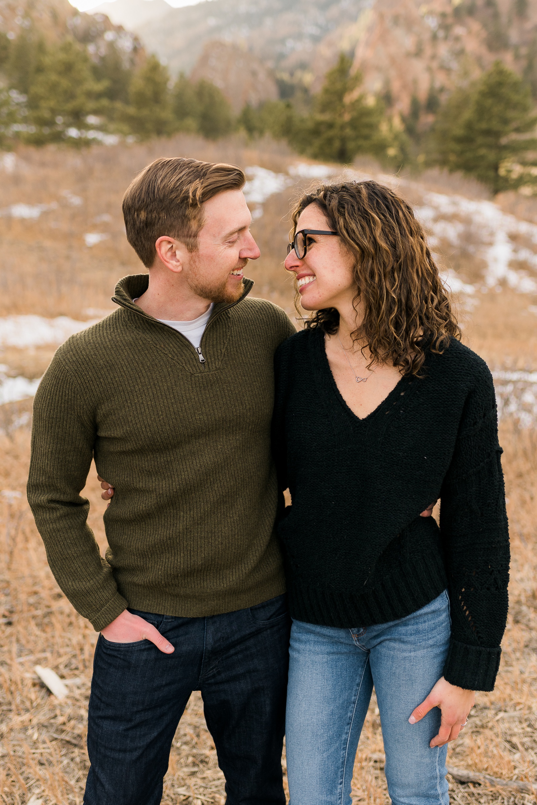 man wearing green sweater and woman in black sweater smiling