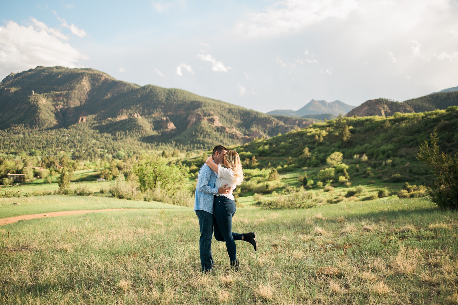 Couple kissing with mountains in background.