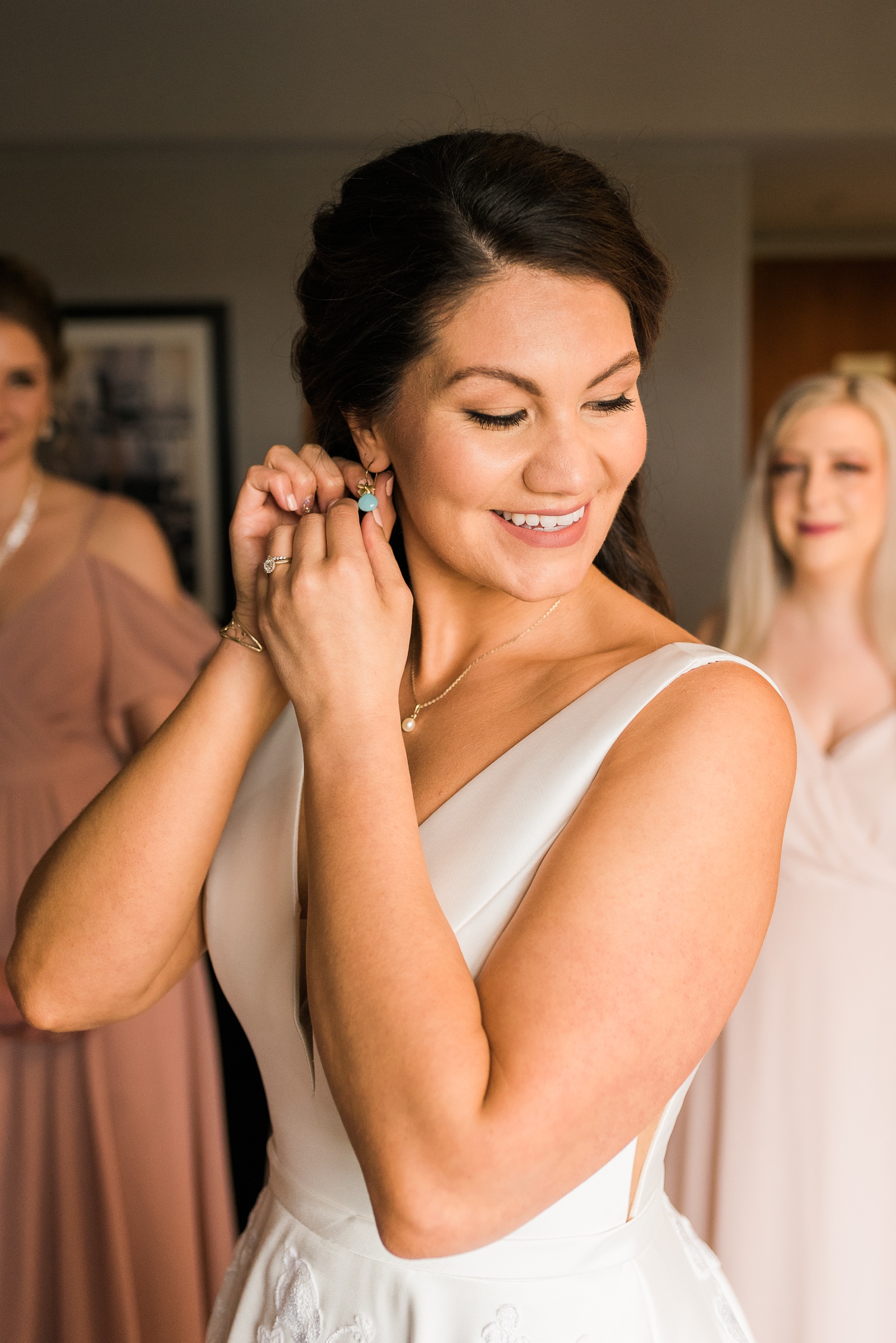 Bride smiling and putting in earrings