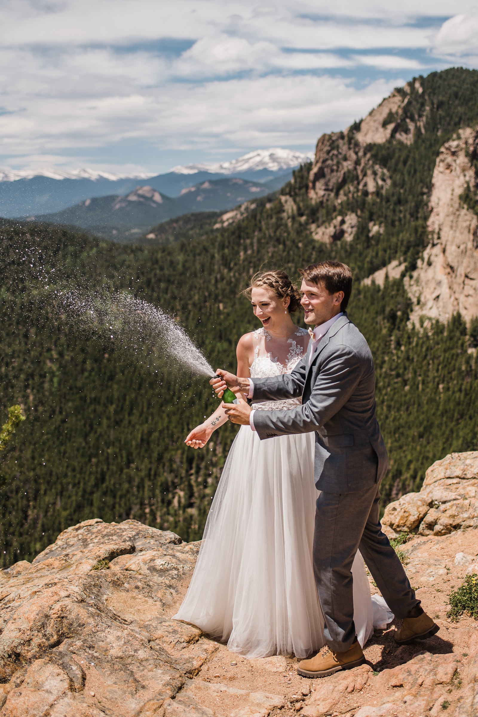 Bride and groom popping champagne on mountain
