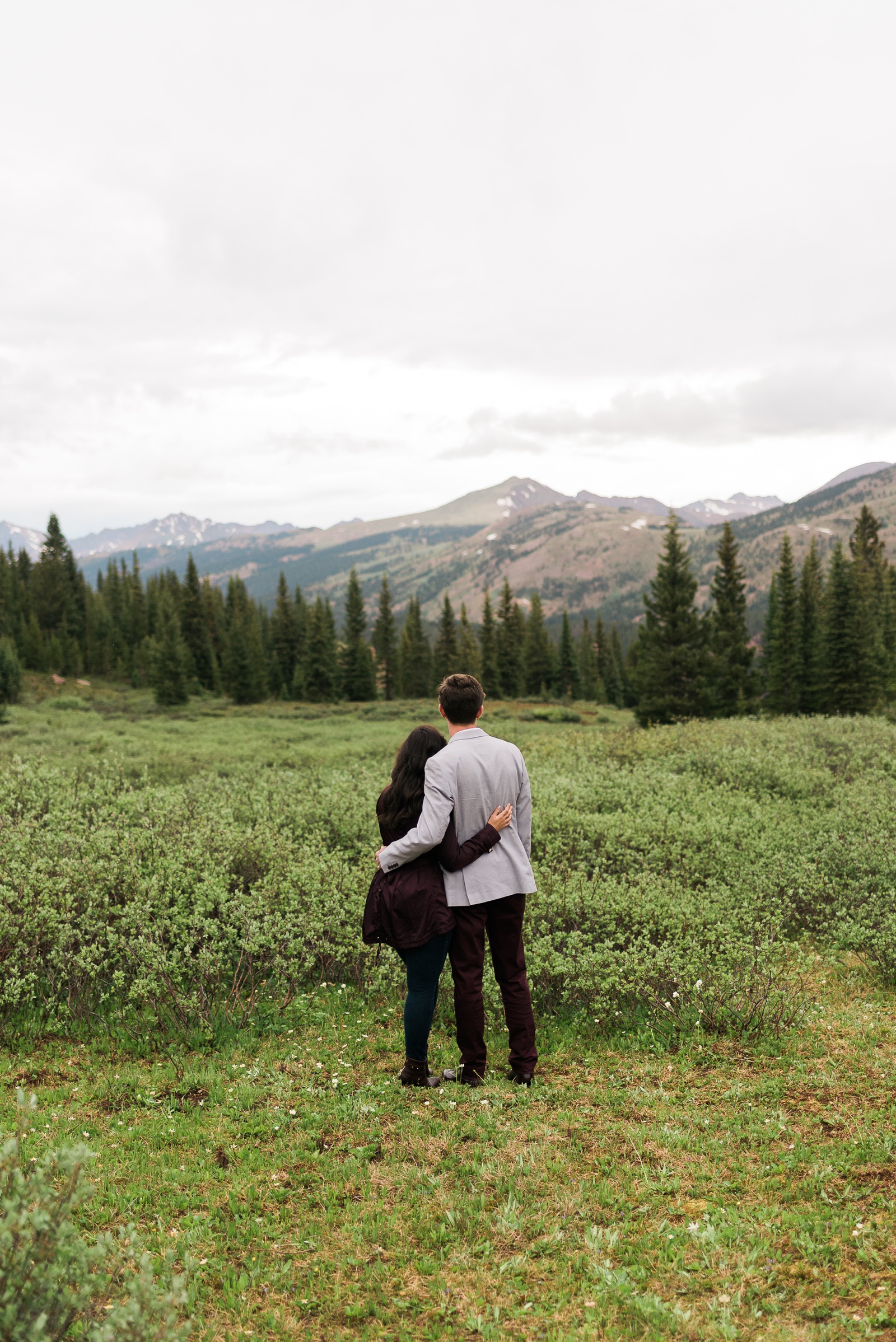 Couple with arms around back looking at mountains