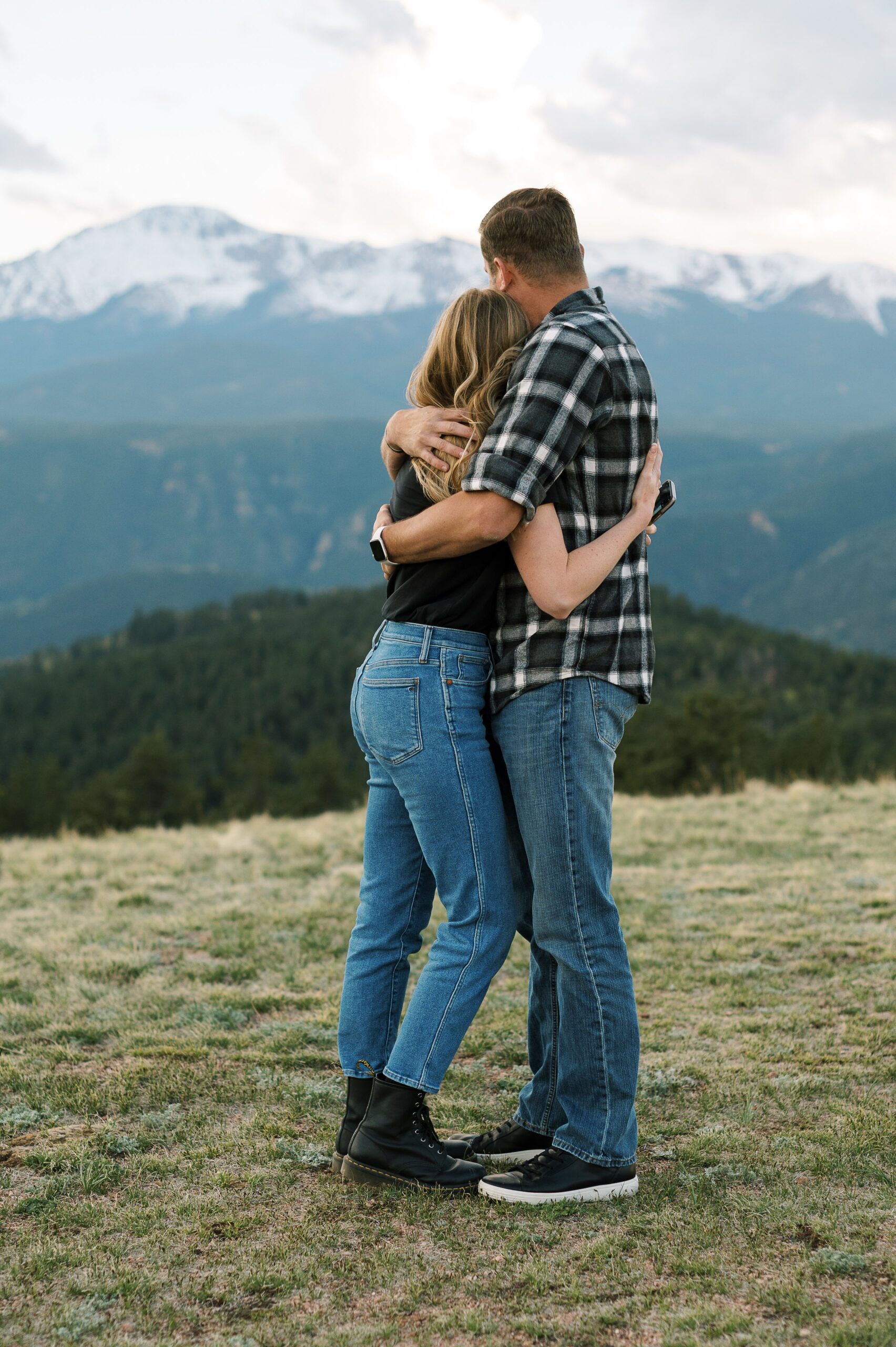 Couple hugging with view of mountains in the background.